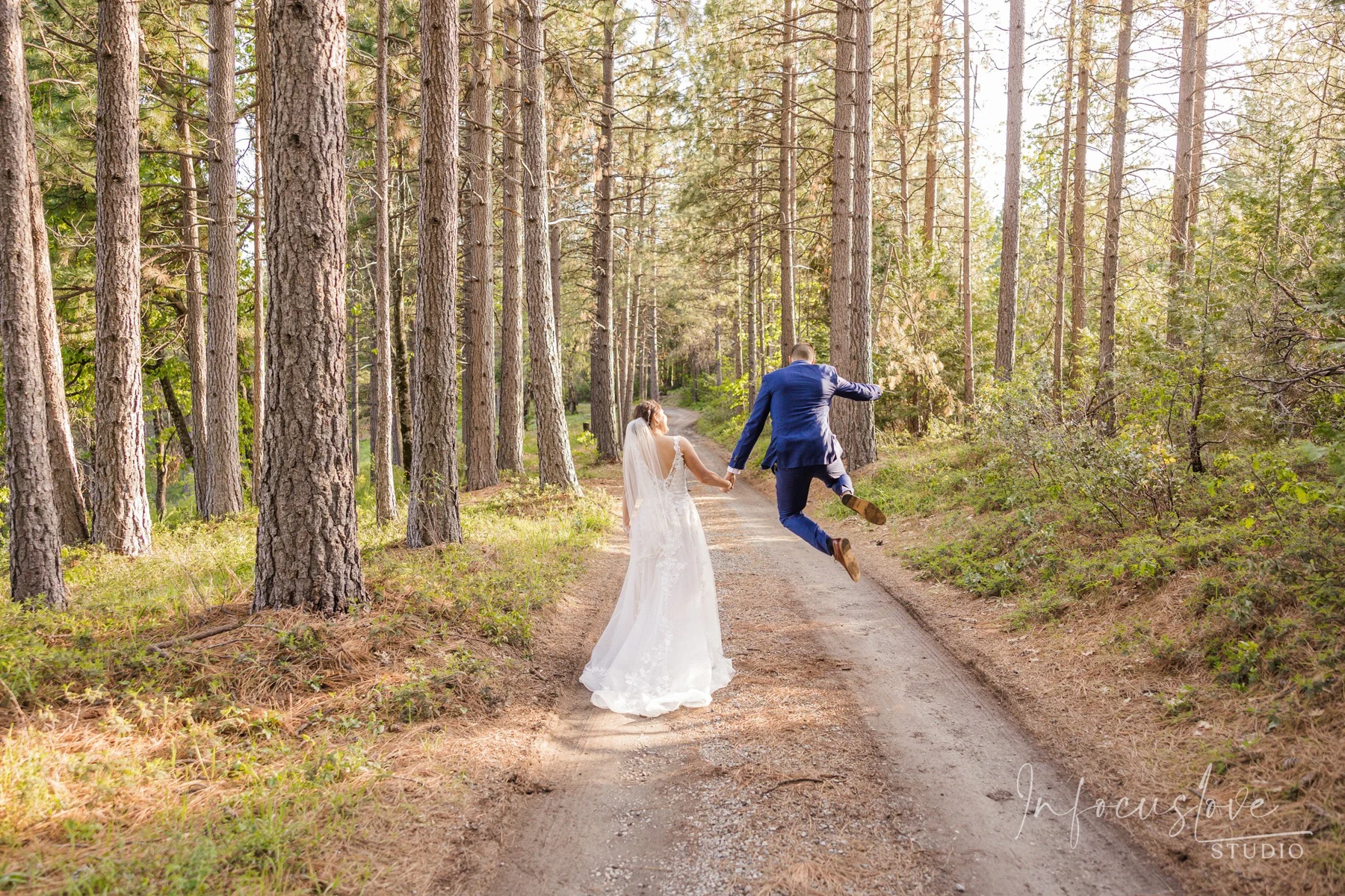 Newlyweds walking along a sunlit forest path